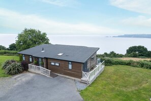 Una casa a due piani con tetto scuro, un balcone e vista sul mare.