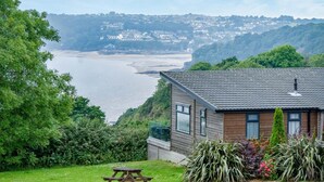 A coastal house with a view of the sea, a picnic table, and lush greenery. - Shearwater 30 - 2 Bedroom Lodge - Summerhill (Narberth)