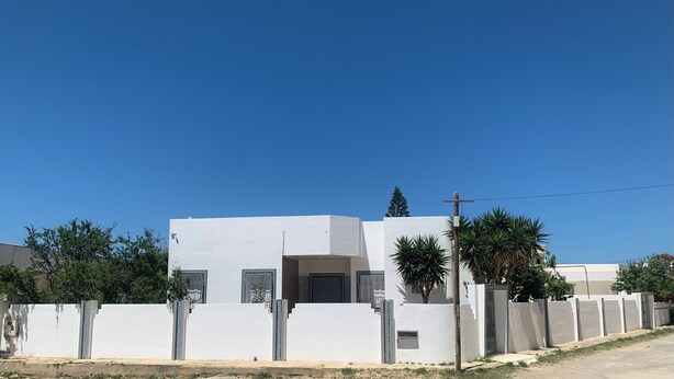 A modern white building with a flat roof, a central entrance, and a gated driveway. - Villa Soliman Plage s+3 (Nabeul)