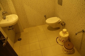 Un baño pequeño con lavamanos, inodoro y un dispensador decorativo de papel higiénico.