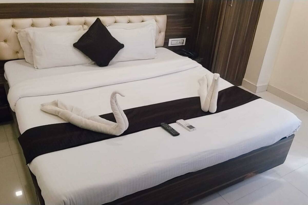 Un letto rifatto con cura, con copriletto bianco e nero, un cuscino nero e un'elegante decorazione con asciugamani a forma di cigno.