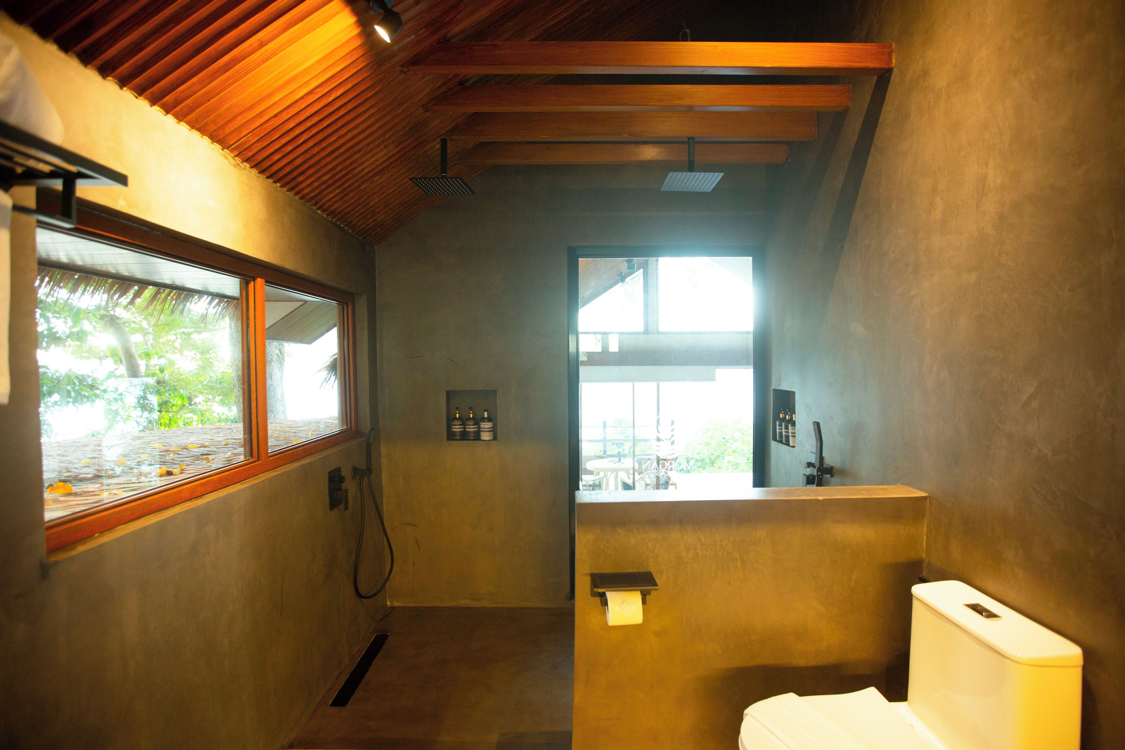A bathroom with a wooden ceiling, a window, and a toilet.
