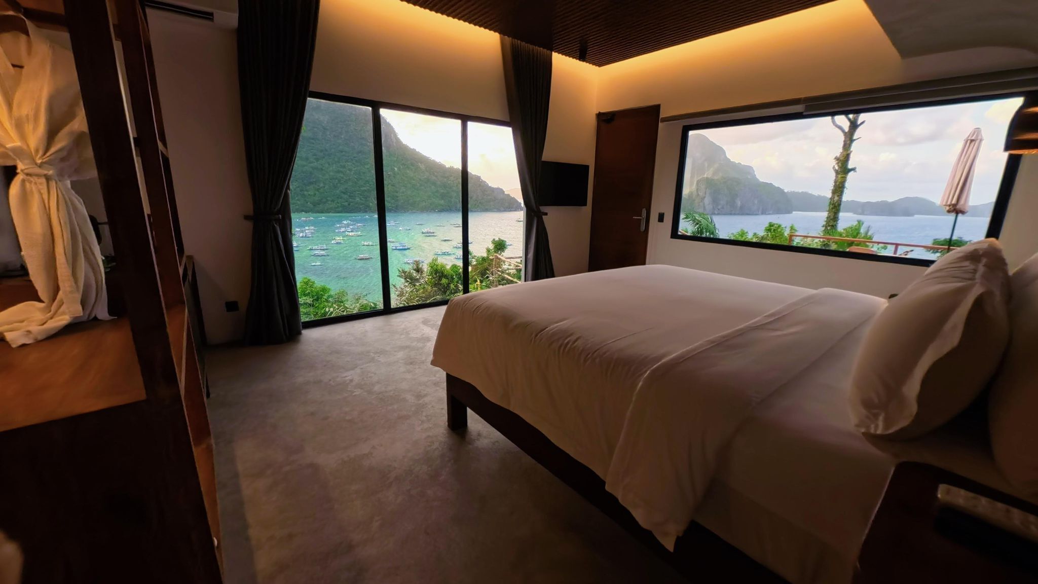 Quarto com cama grande, vista para o mar e varanda.