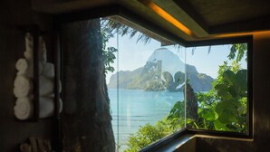 Una habitación con un ventanal que ofrece vistas a un paisaje montañoso y una masa de agua.