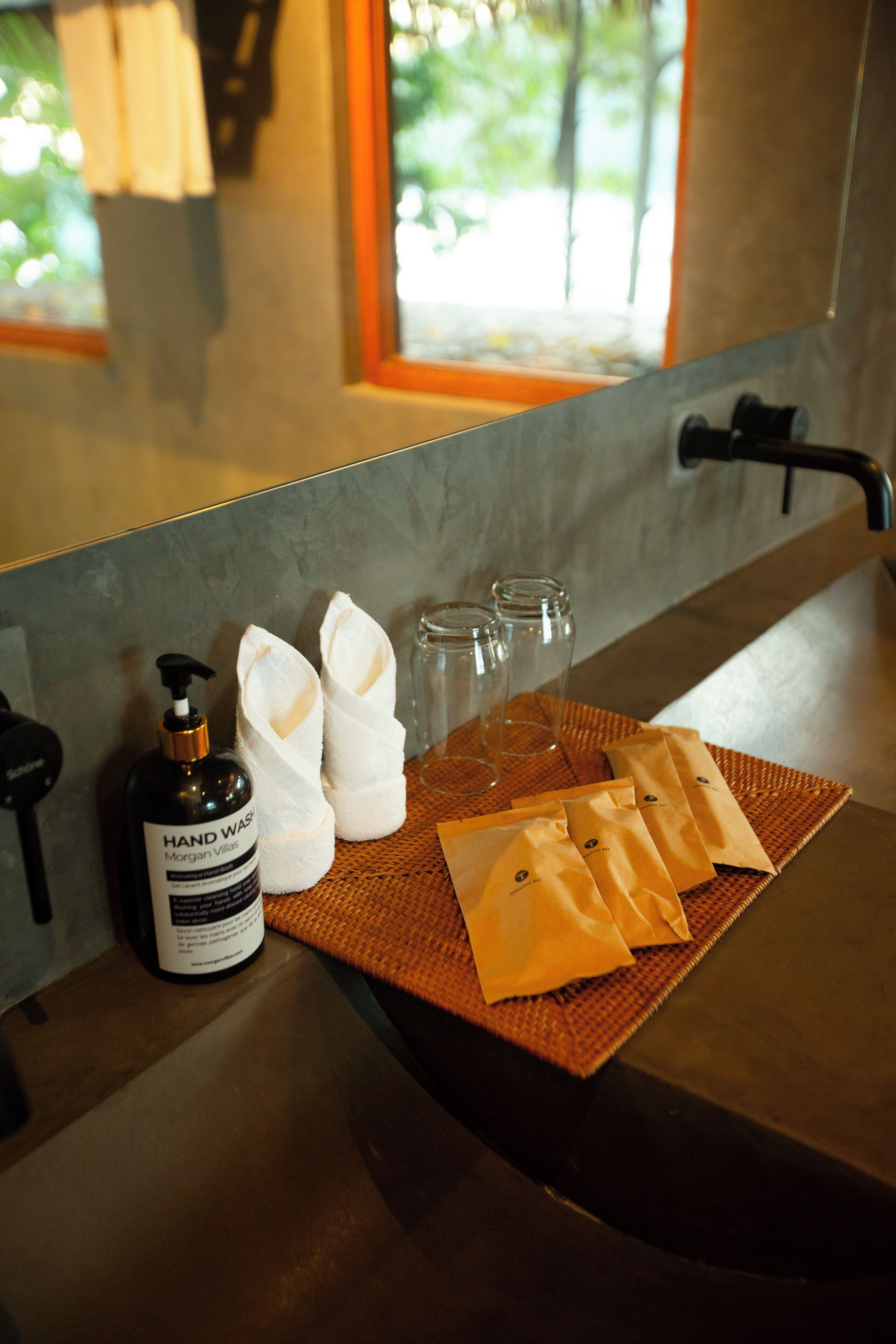 Un meuble-lavabo dans une salle de bain, avec du savon liquide, des serviettes et des verres.