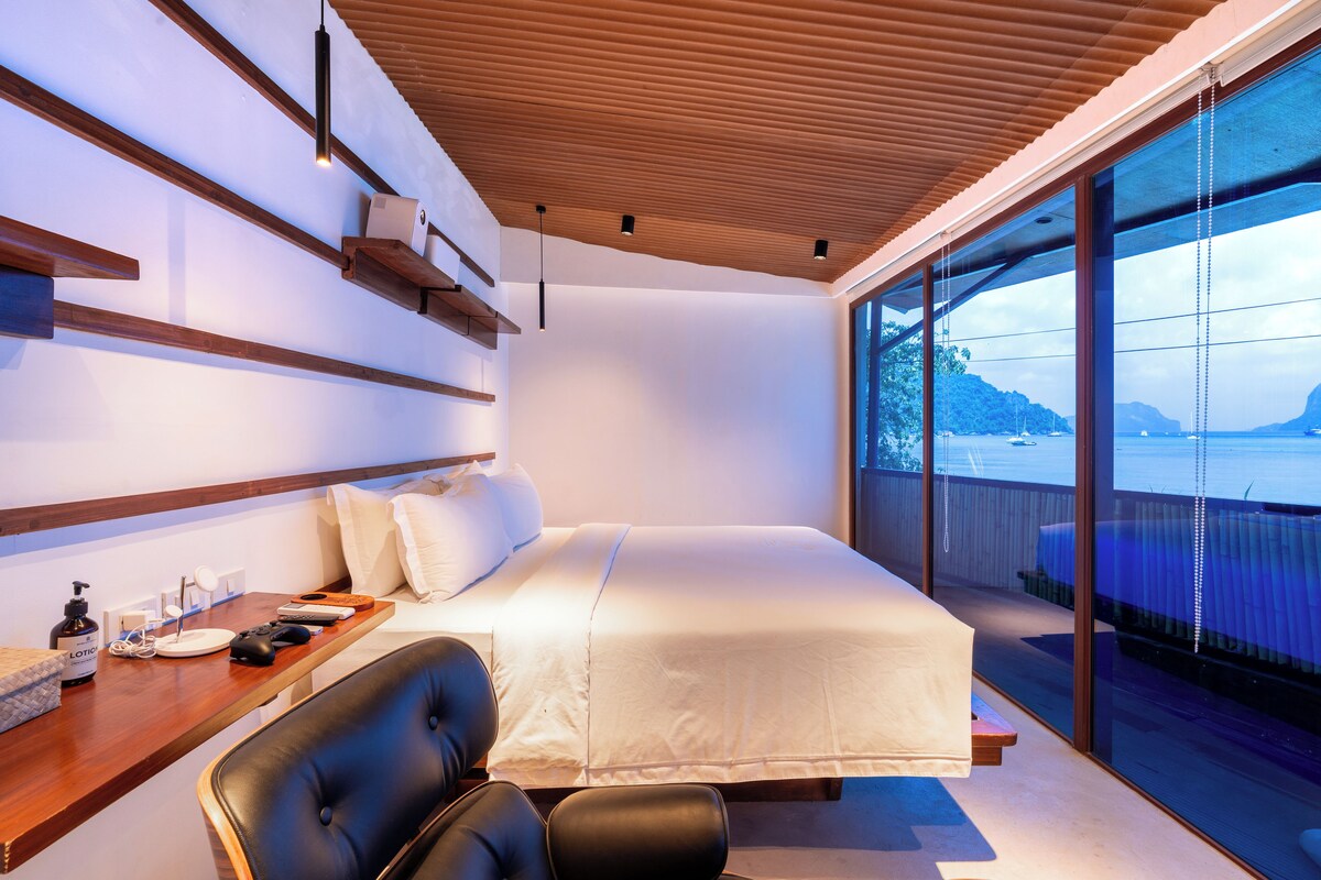 Une chambre moderne avec un grand lit, un bureau avec un ordinateur et une vue sur la mer.