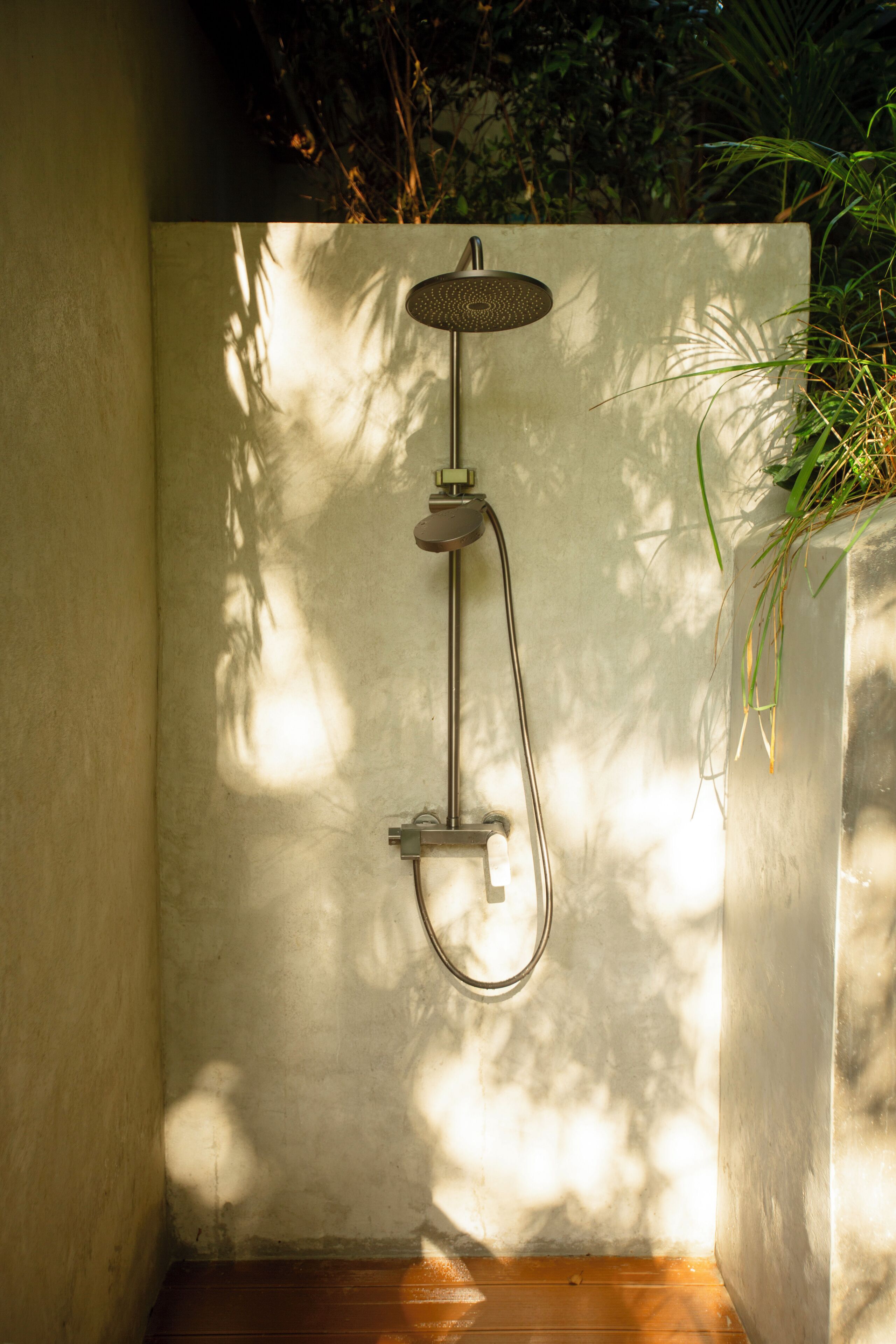 Een moderne douche met een regendouchekop, een handdouche en een handmatige doucheaansluiting.