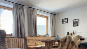Un salon chaleureux avec un fauteuil gris, un tapis rond, une table à manger en bois et des chaises.