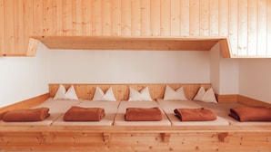 Une pièce en bois avec un plafond en pente, un lit avec des oreillers blancs et des serviettes marron.