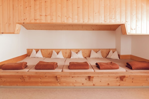 A wooden room with a sloped ceiling, a bed with white pillows, and brown towels.