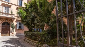 A cobblestone street with a wrought iron gate, a building with a balcony, and lush greenery. - Napolehome Luxury Apartment in the center of Rome (Roma)