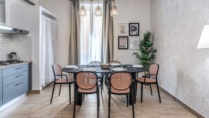 A dining area with a round table, six wicker chairs, and hanging pendant lights. - Napolehome Luxury Apartment in the center of Rome (Roma)