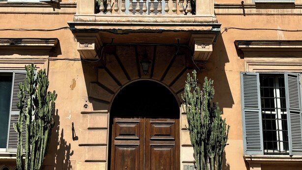A building with a central entrance, multiple windows with shutters, and potted cacti on the ground floor. - Napolehome Luxury Apartment in the center of Rome (Roma)