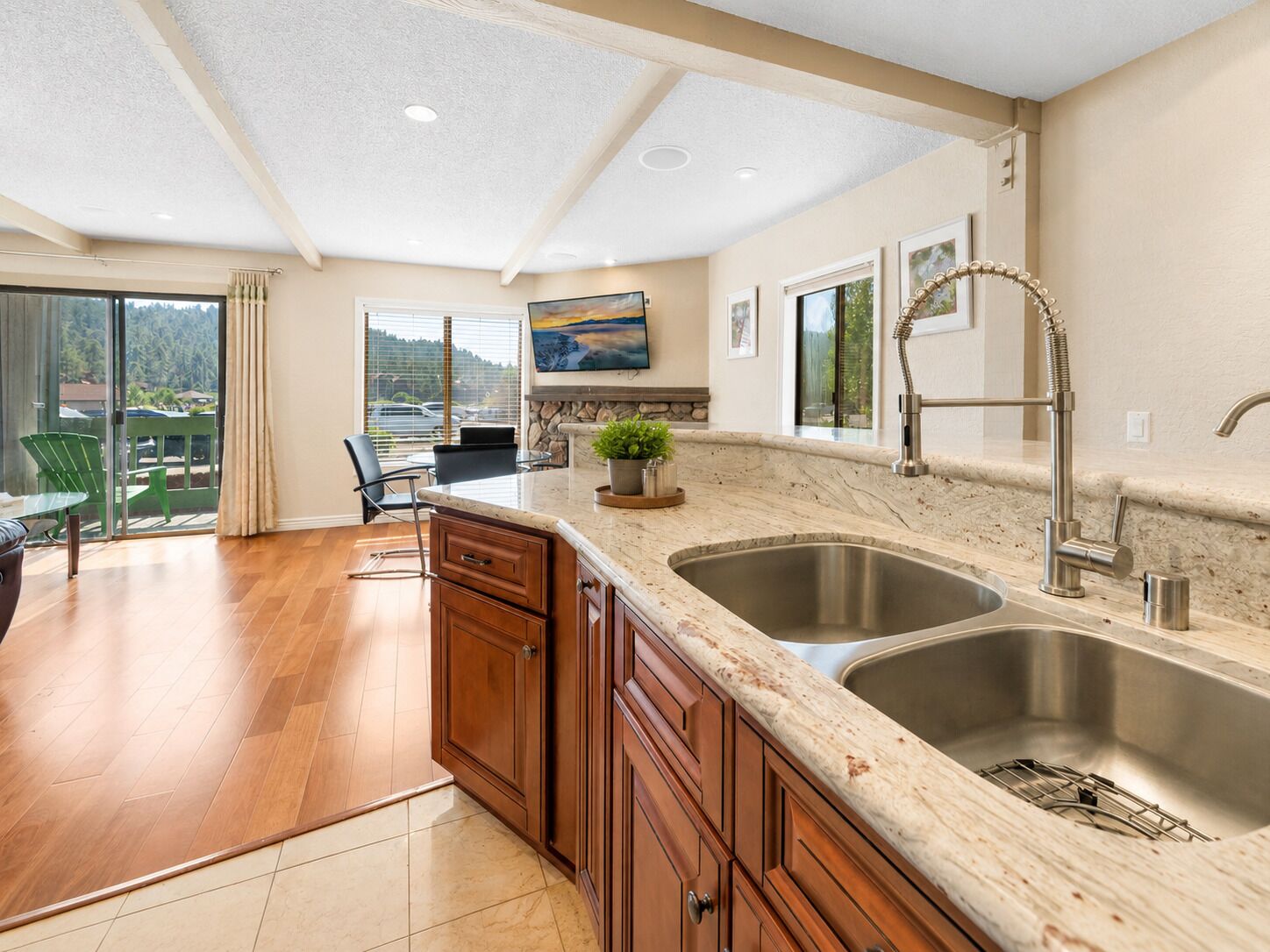 A kitchen with a large island, double sinks, and a view of a balcony.