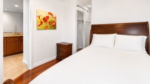 Ein Schlafzimmer mit einem Holzbett, einem Nachttisch, einem Gemälde und einem Badezimmer mit Dusche.