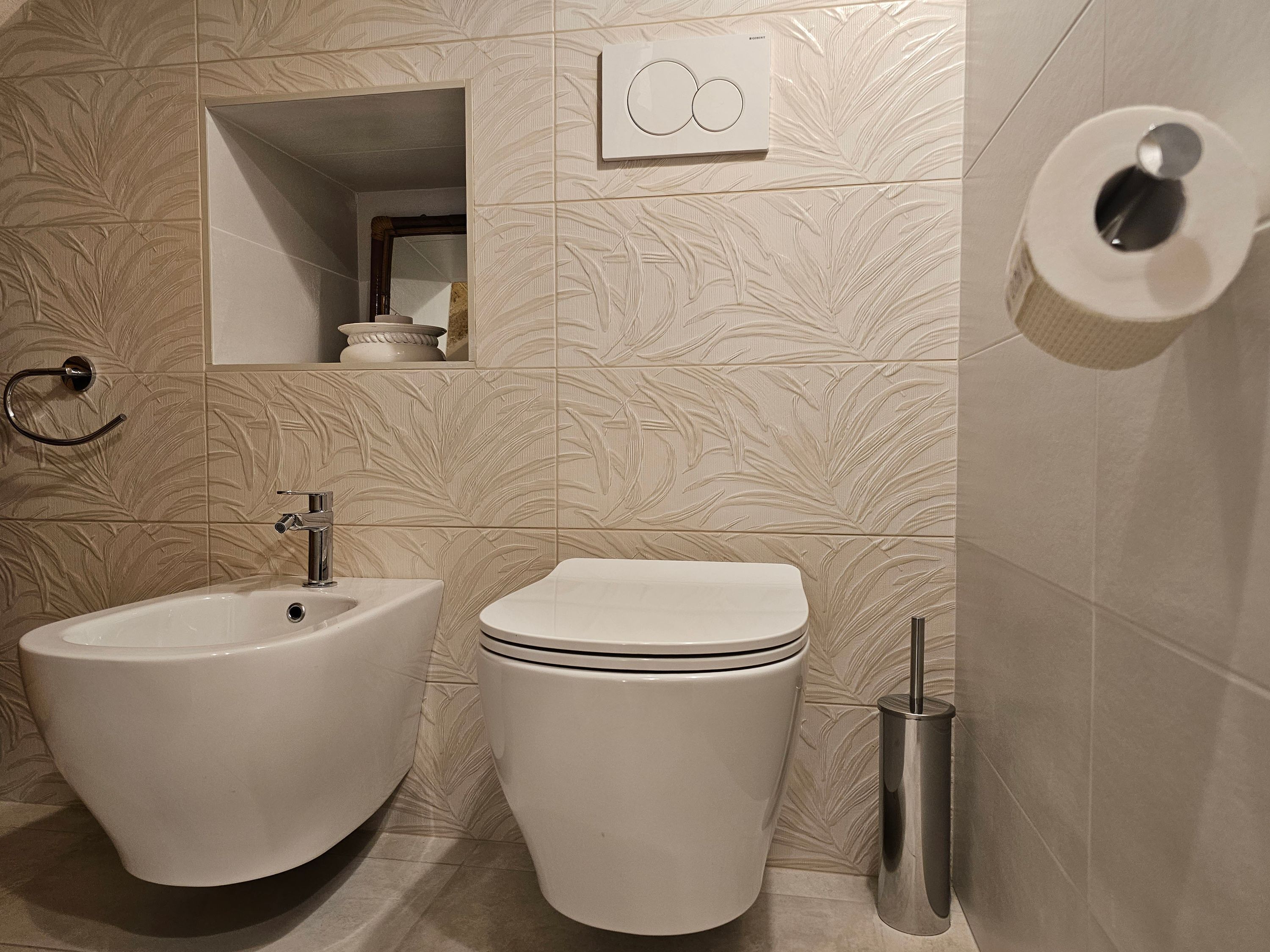 A bathroom with a bidet, toilet, and a towel rack.