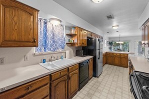 Una cocina moderna con armarios de madera, un refrigerador negro y un lavavajillas.
