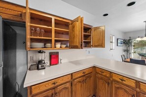 Une cuisine avec des meubles en bois, un plan de travail blanc et un meuble à vin intégré.