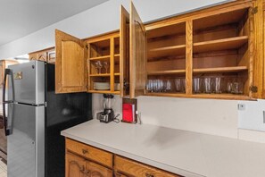 Eine Küche mit Holzschränken, einem Kühlschrank und einer Arbeitsplatte mit einem Mixer.