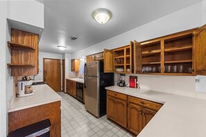 Eine Küche mit Holzausstattung, einem Kühlschrank, einer Kaffeemaschine und einem Mixer.