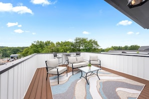 A rooftop deck with outdoor furniture, a patterned rug, and a clear view of the surrounding landscape. - Urban Rooftop of Downtown (1014 Franklin St) (Clarksville)