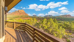 A wooden deck with a view of red rock formations and green vegetation. - Red Rock Vista | Incredible Views, Hot Tub, Firepit, Trails (Sedona)