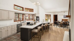 A spacious kitchen with a large island, wooden cabinets, and a dining area with a wooden table and chairs. - Red Rock Vista | Incredible Views, Hot Tub, Firepit, Trails (Sedona)