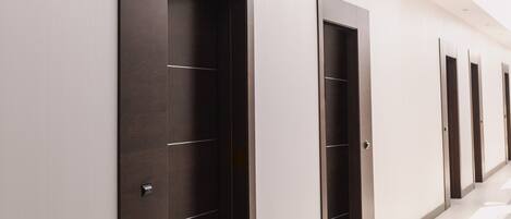 A corridor with doors, each with a handle and a keyhole.