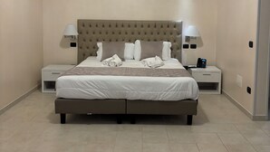 Une chambre à coucher avec un grand lit, deux tables de chevet, une tête de lit et un luminaire au plafond.