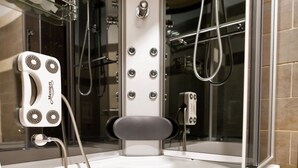 Une salle de bain moderne dotée d’une douche à parois de verre, d’un fauteuil de massage et d’un pommeau de douche à main.