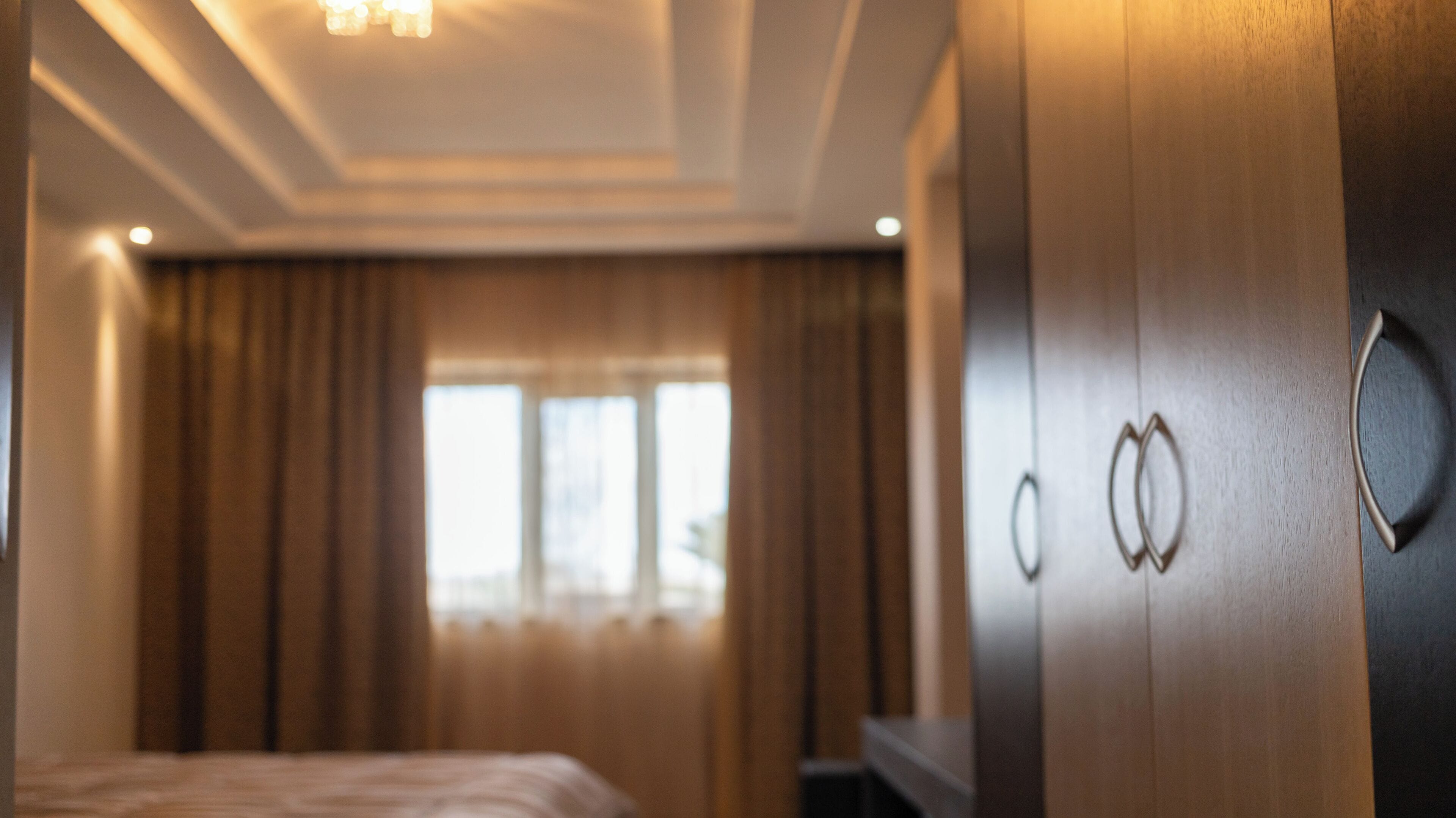 Ein Hotelzimmer mit einem Bett, einem Kleiderschrank und einem fenster mit Vorhängen.