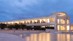 Un hotel moderno con fachada curva, varios balcones y un amplio patio.
