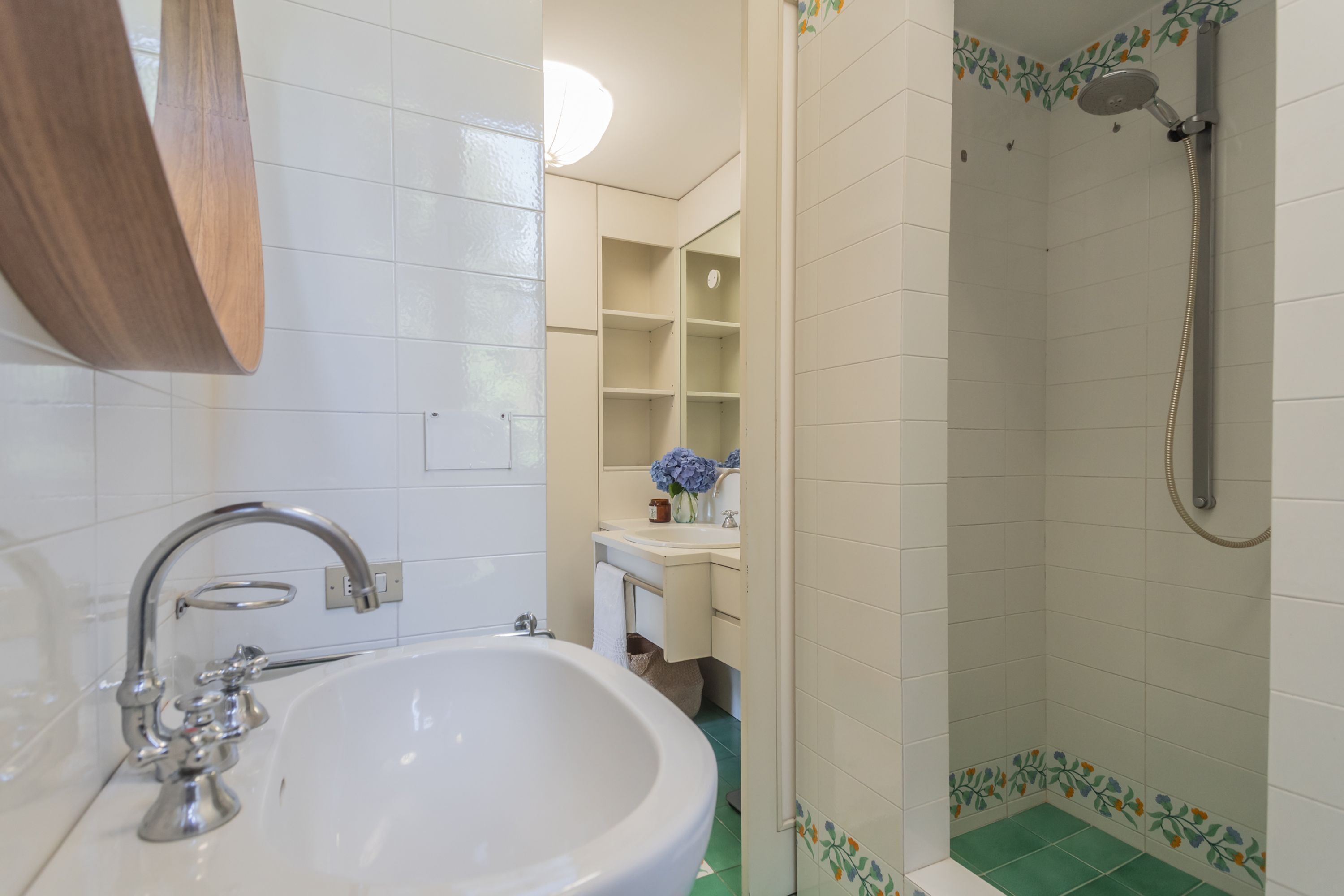 Un baño con lavamanos, espejo y ducha.