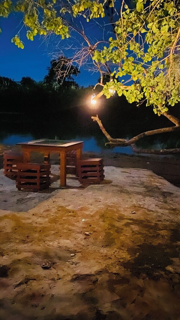A wooden table and chairs under a tree at night.