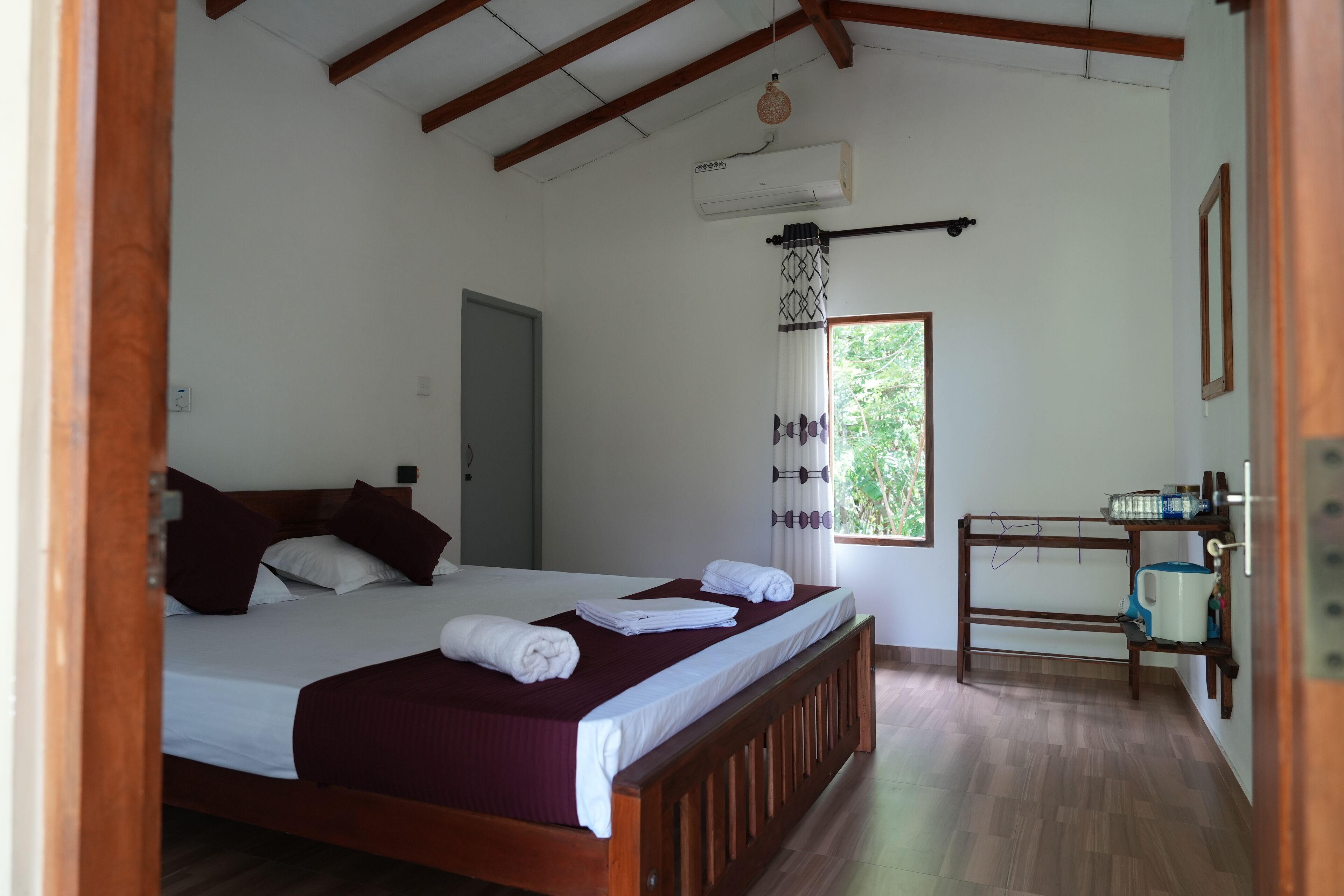 Un dormitorio con una cama de madera, ropa de cama blanca, una ventana con vistas y una pequeña zona de kitchenette.