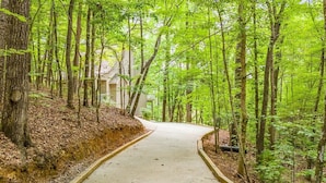 A forested pathway leading to a building with a light-colored exterior. - Alpine Chalet| 5BR | Helen, GA| near golf| community pool (Helen)