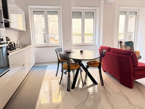 Een moderne keuken met witte kasten, een eettafel met stoelen en een rode bank.