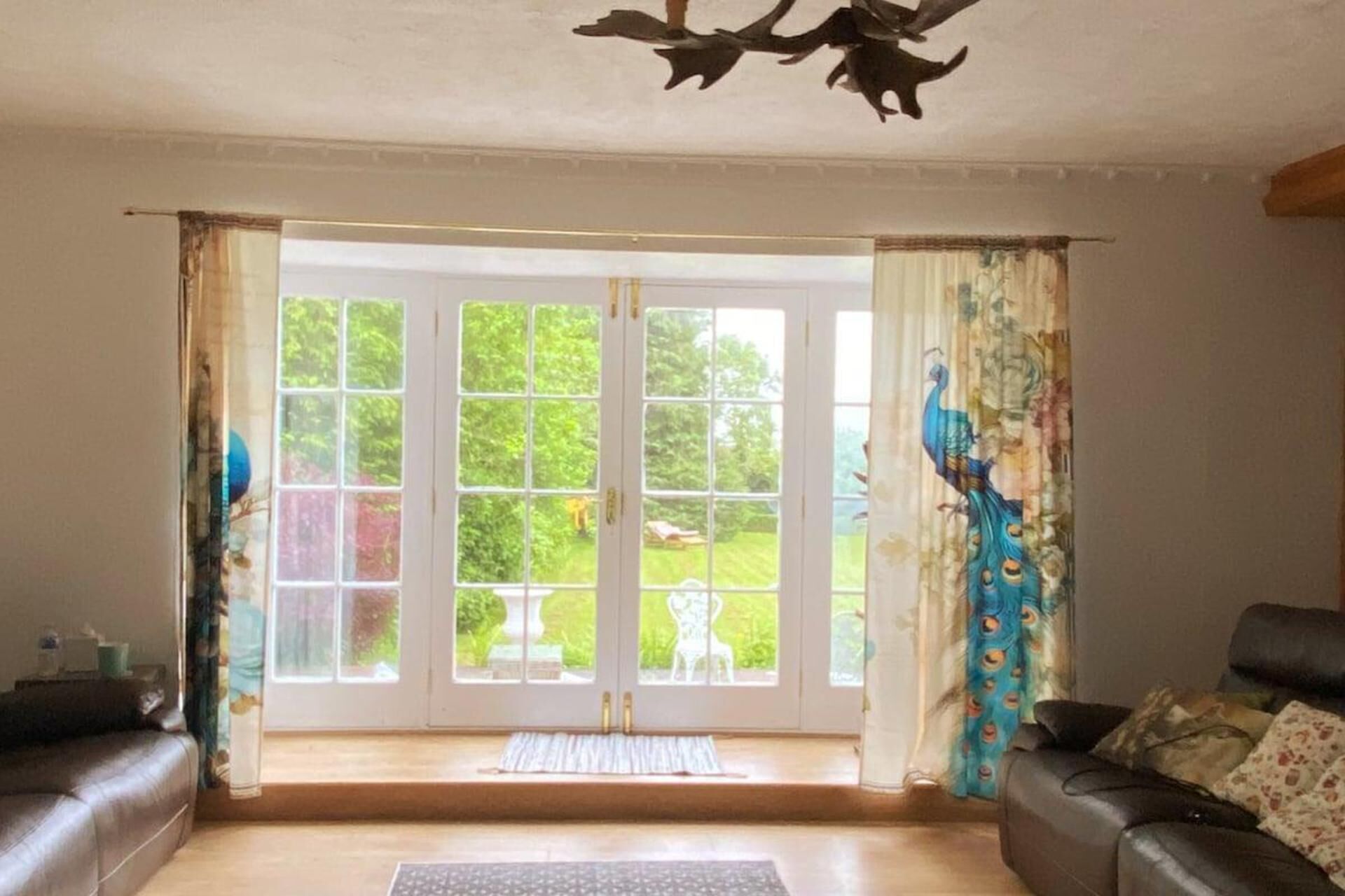 A living room with a large sliding glass door leading to a garden. There are two sofas and a coffee table.