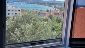 A window with a view of a coastal area, buildings, and trees. - Holiday Home 'Chez Cisco' with Sea View, Wi-Fi and Air Conditioning (le lavandou)