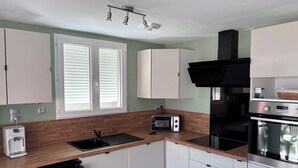 A modern kitchen with white cabinets, a built-in microwave, a coffee maker, and a dishwasher. - Holiday Home 'Chez Cisco' with Sea View, Wi-Fi and Air Conditioning (le lavandou)