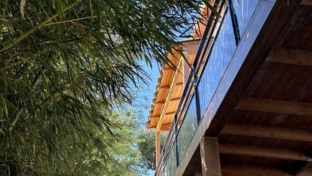 A modern building with a wooden facade, a staircase leading to a second floor, and a view of the surrounding greenery. - Holiday Home 'Chez Cisco' with Sea View, Wi-Fi and Air Conditioning (le lavandou)