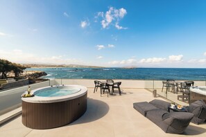 Una terraza en la azotea con bañera de hidromasaje, mobiliario exterior y vistas al mar.