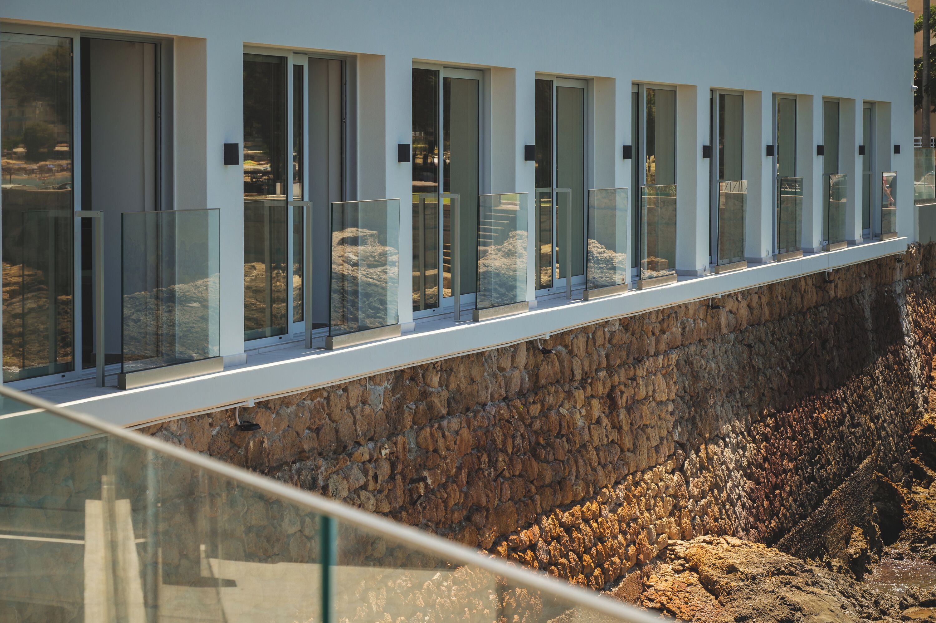 A modern building with a long balcony overlooking a rocky landscape.