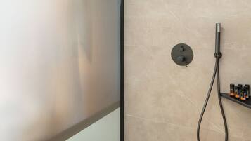 Un baño moderno con ducha, un lavabo redondo y un taburete pequeño.
