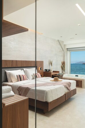 Un dormitorio moderno con una cama grande, mesitas de noche y vistas al mar.