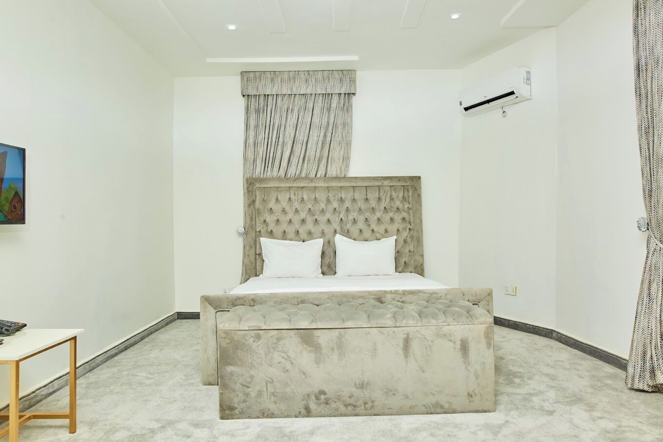 Ein Schlafzimmer mit einem großen Bett, einem Nachttisch, einer Wandklimaanlage und einem Gemälde an der Wand.