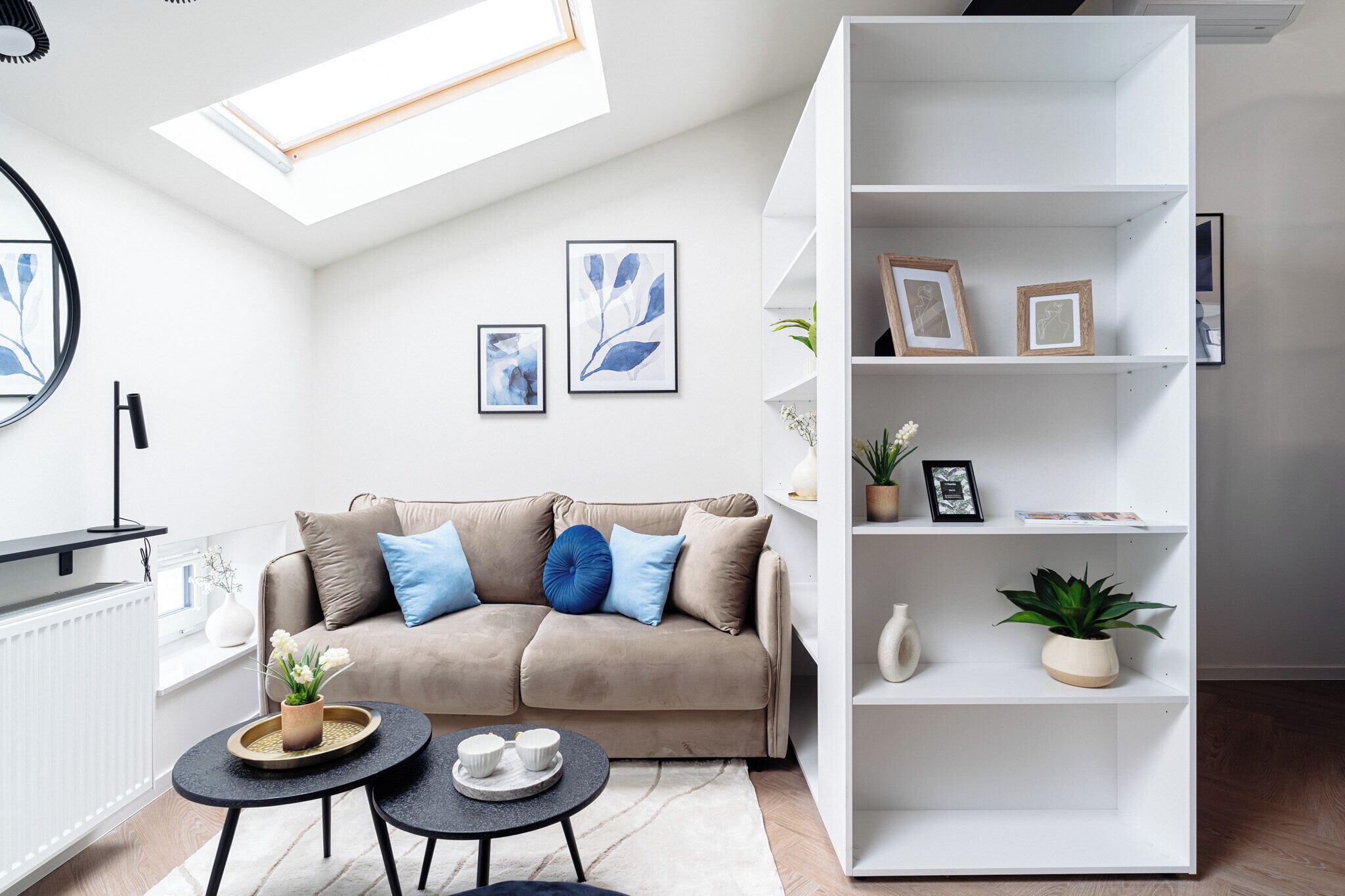 A modern living room with a sofa, a coffee table, a bookshelf, and framed artwork on the wall.