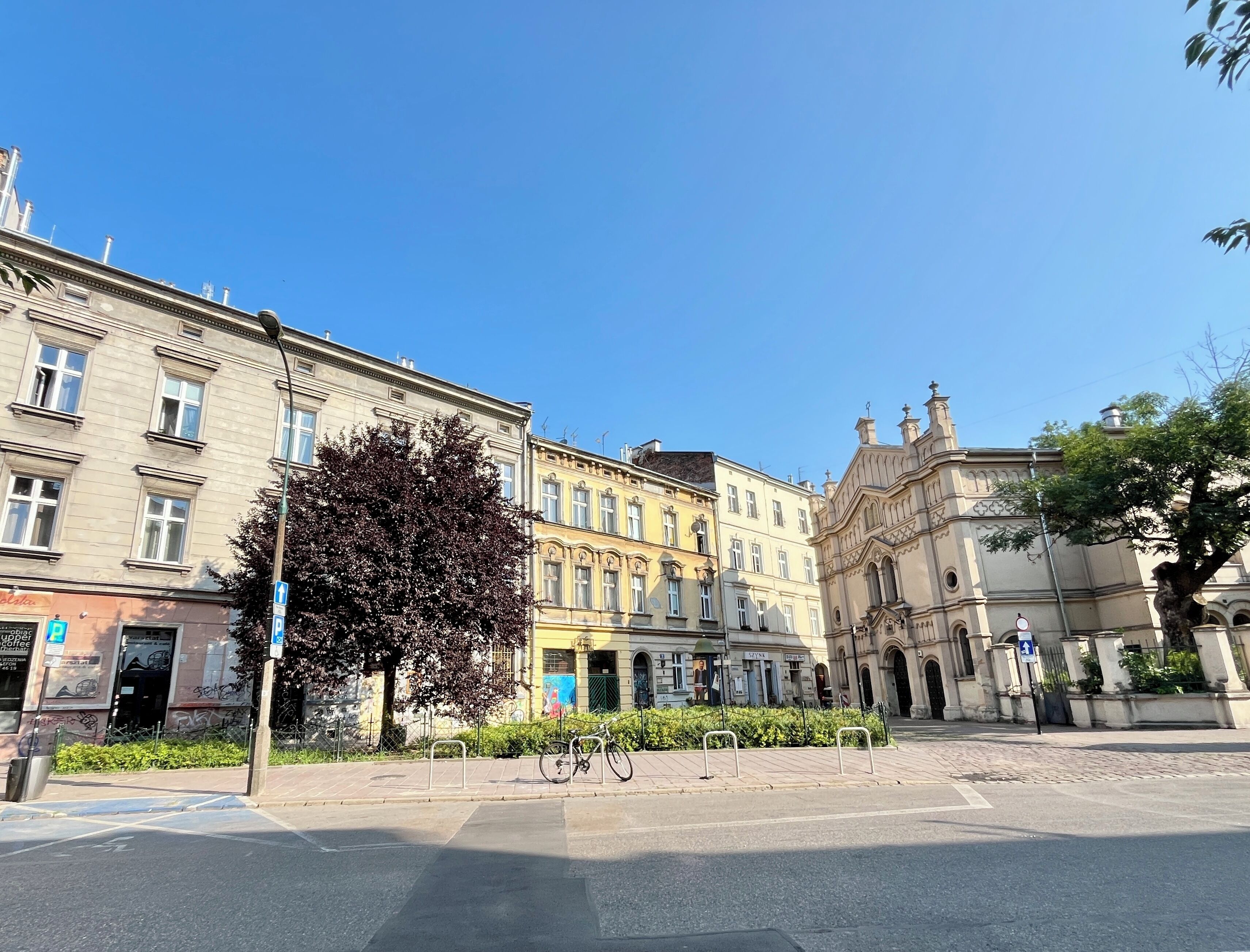 Une rue bordée d’immeubles historiques, avec un arbre et un vélo.