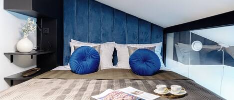 Un dormitorio moderno con una cama grande, una mesita de noche, un florero con flores y una ventana con vistas.