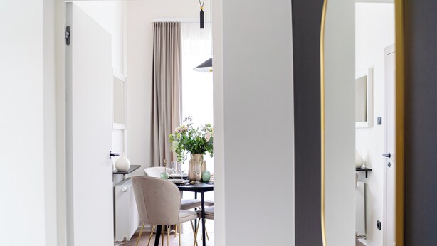 A modern dining area with a table set for two, a chair, and a vase of flowers. - Miodova20 by StayLab (Kraków)